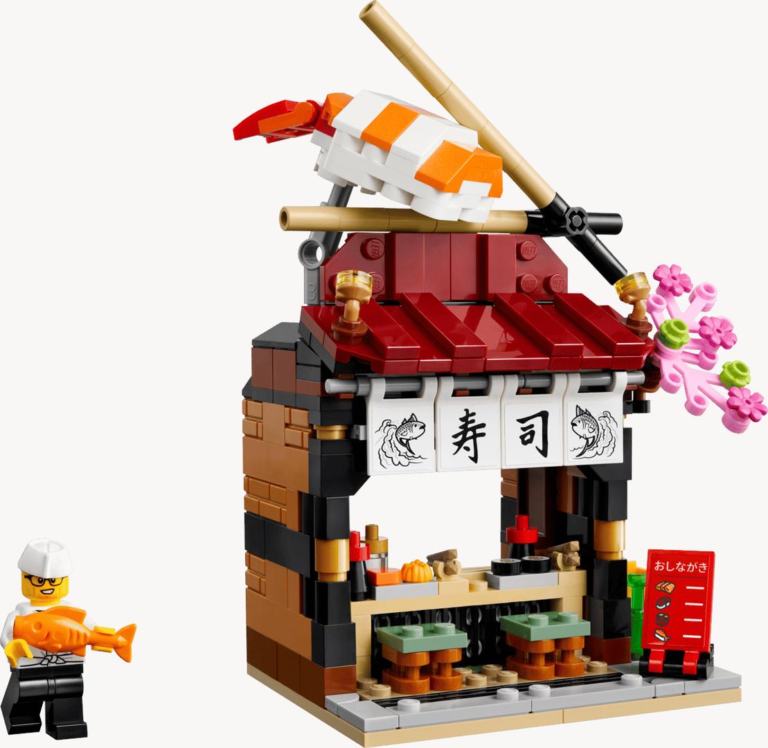 世界のレストラン：日本40906の公式製品画像。握り寿司と箸を屋根に載せ、「寿司」ののれんやお品書きを備えた店。画像：レゴグループ（Brimagaカタログ掲載画像）。